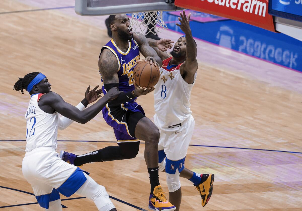 Lakers forward LeBron James drives to the basket against Pelicans forwards Wenyen Gabriel and Naji Marshall.