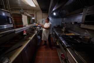 A chef works on breakfast orders in a kitchen at a restaurant.
