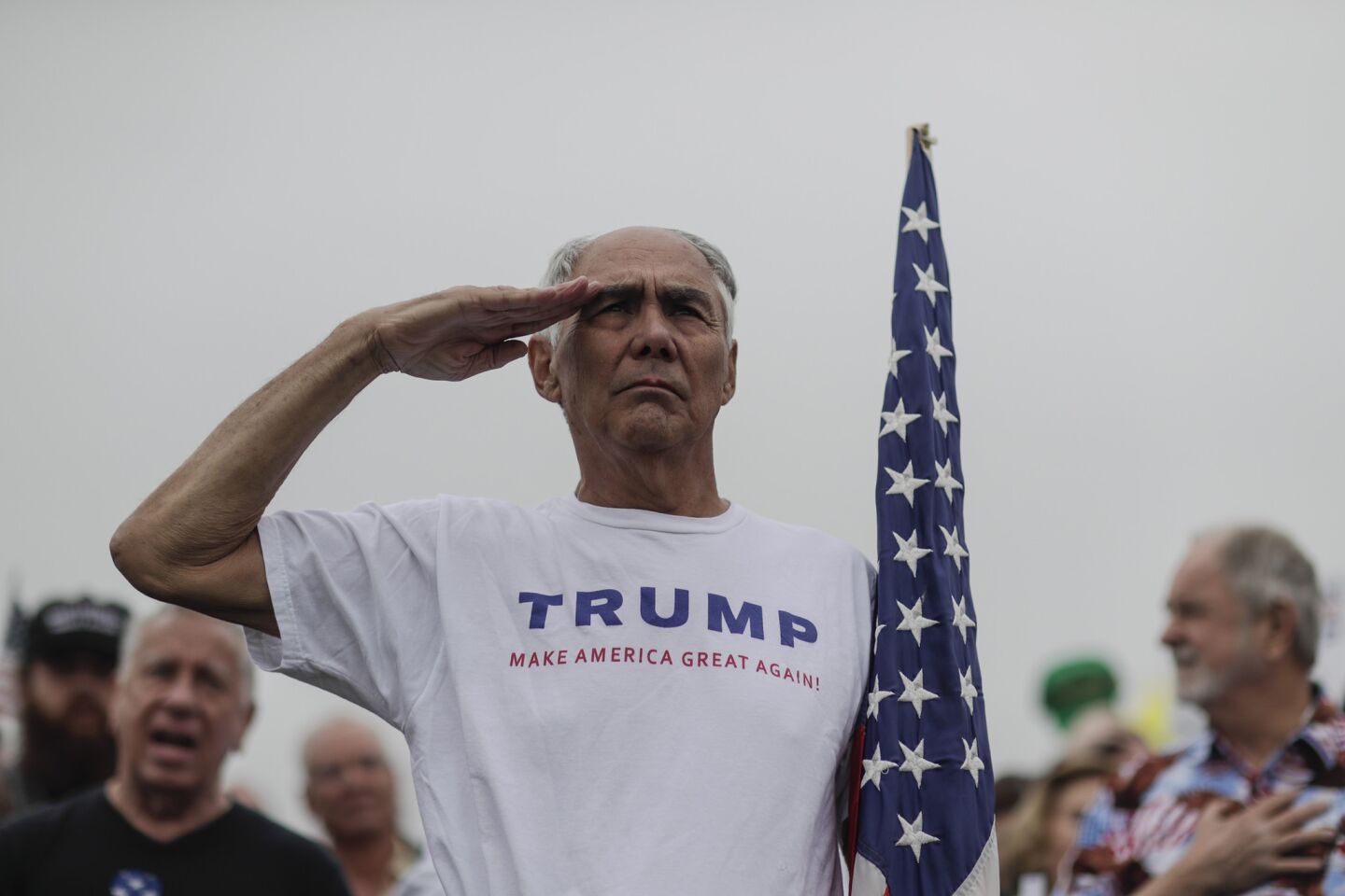 Adrian Asencio, 73, from Redlands, salutes as the National Anthem is played for a rally supporting President Trump a few miles away from the border wall prototypes near San Diego.