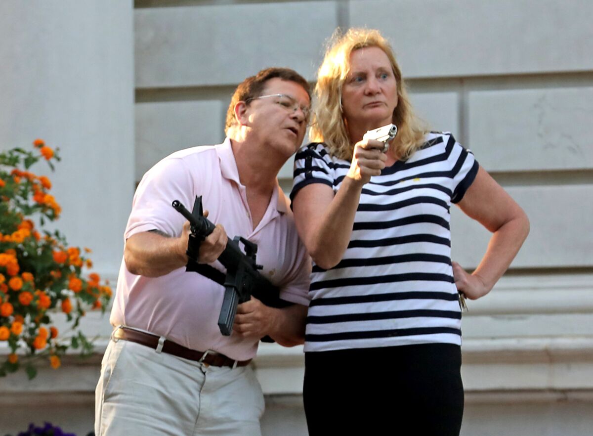 Mark and Patricia McCloskey point guns at protestors marching by their St. Louis mansion in June.