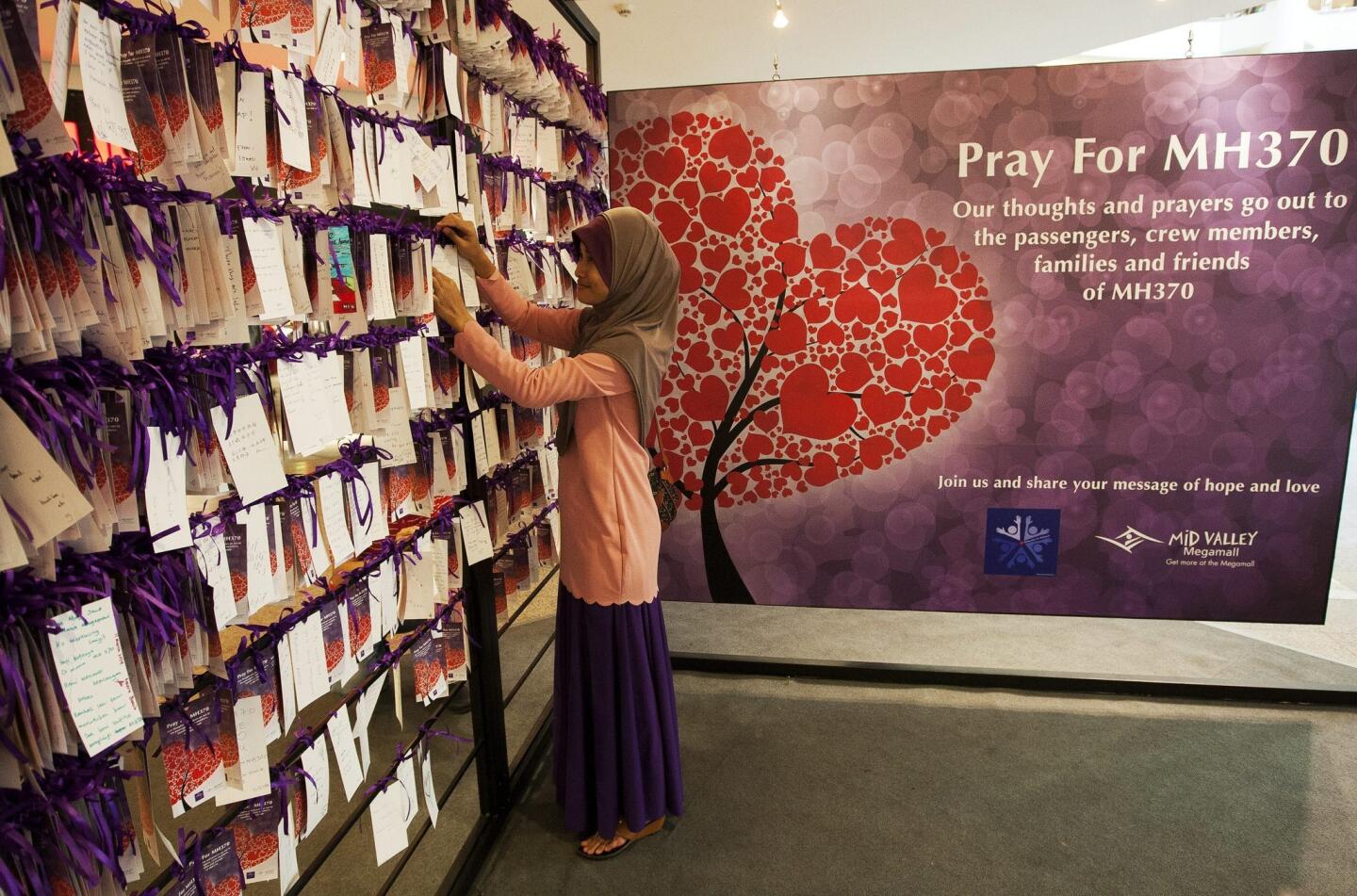 A visitor hangs a message of hope for passengers and crew of the missing Malaysian Airline plane at a shopping mall in Kuala Lumpur, Malaysia, 19 March 2014.