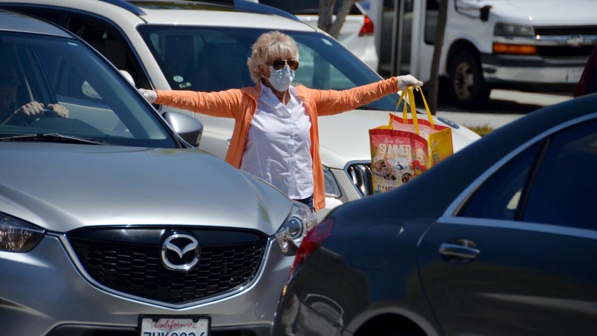 Newport Beach City Councilwoman Joy Brenner pitches in during a drive-by mask giveaway Thursday outside the Oasis Senior Center in Corona del Mar.