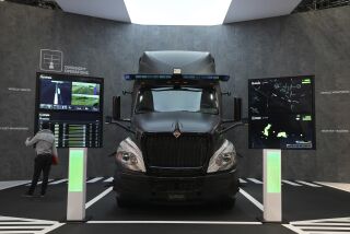 A person looks at the TuSimple autonomous driving technology on a truck on display during the CES tech show Thursday, Jan. 6, 2022, in Las Vegas. The technology is designed for commercial-ready, fully autonomous driving for long-haul heavy-duty trucks. (AP Photo/Joe Buglewicz)