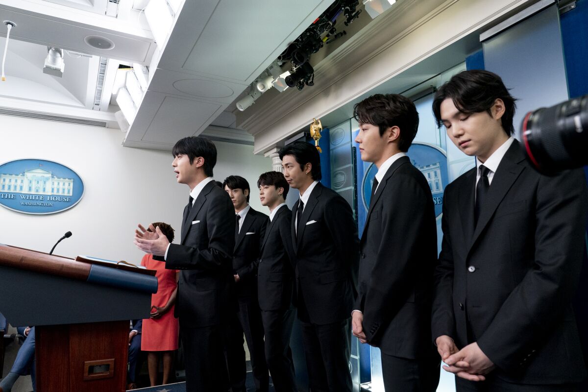 A K-pop group dressed in suits at a press conference