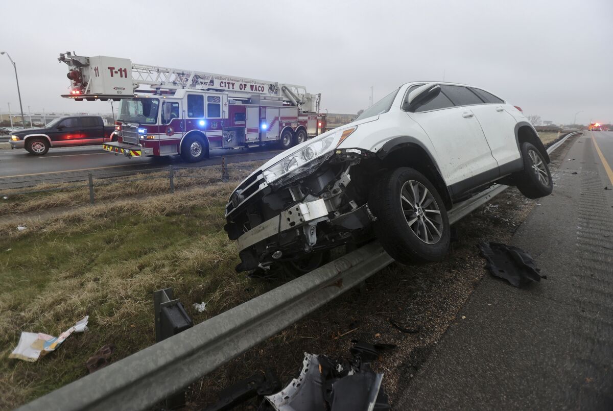 Damaged vehicle sits on a guardrail after a weather-related crash.