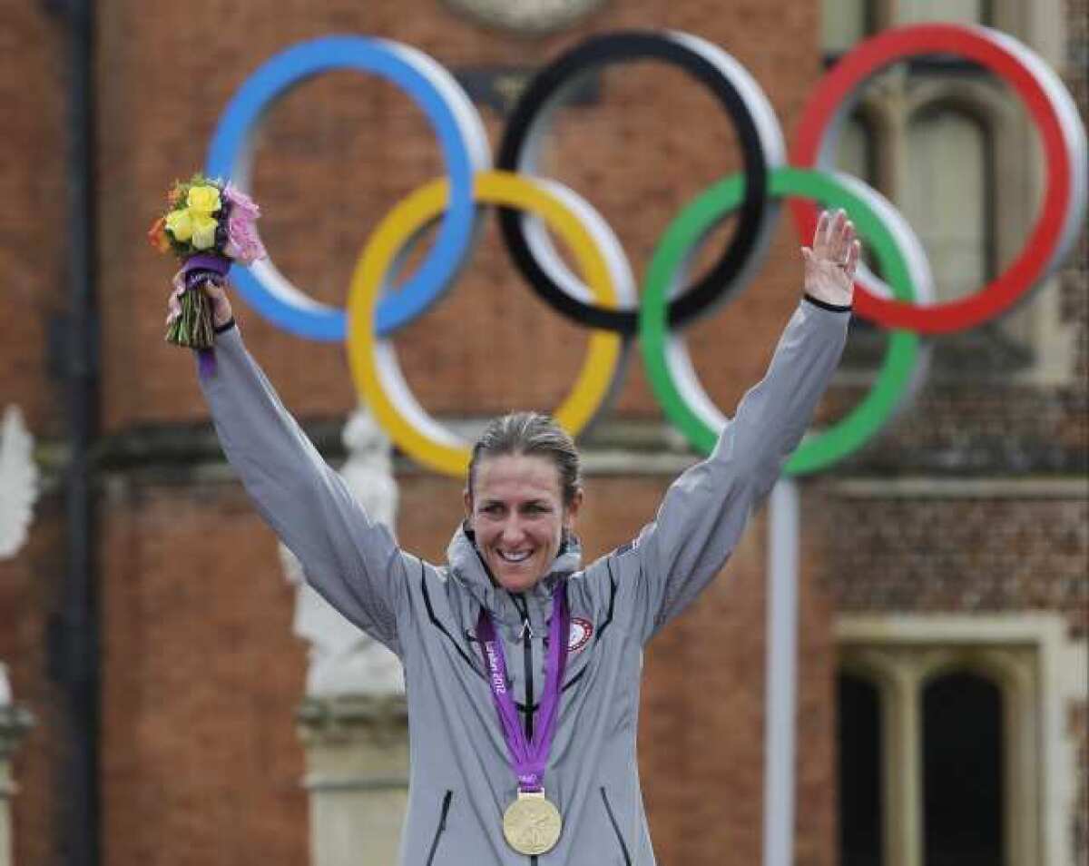 Road cyclist Kristin Armstrong, a former triathlete, triumphantly displays her gold medal in women's individual time trial.