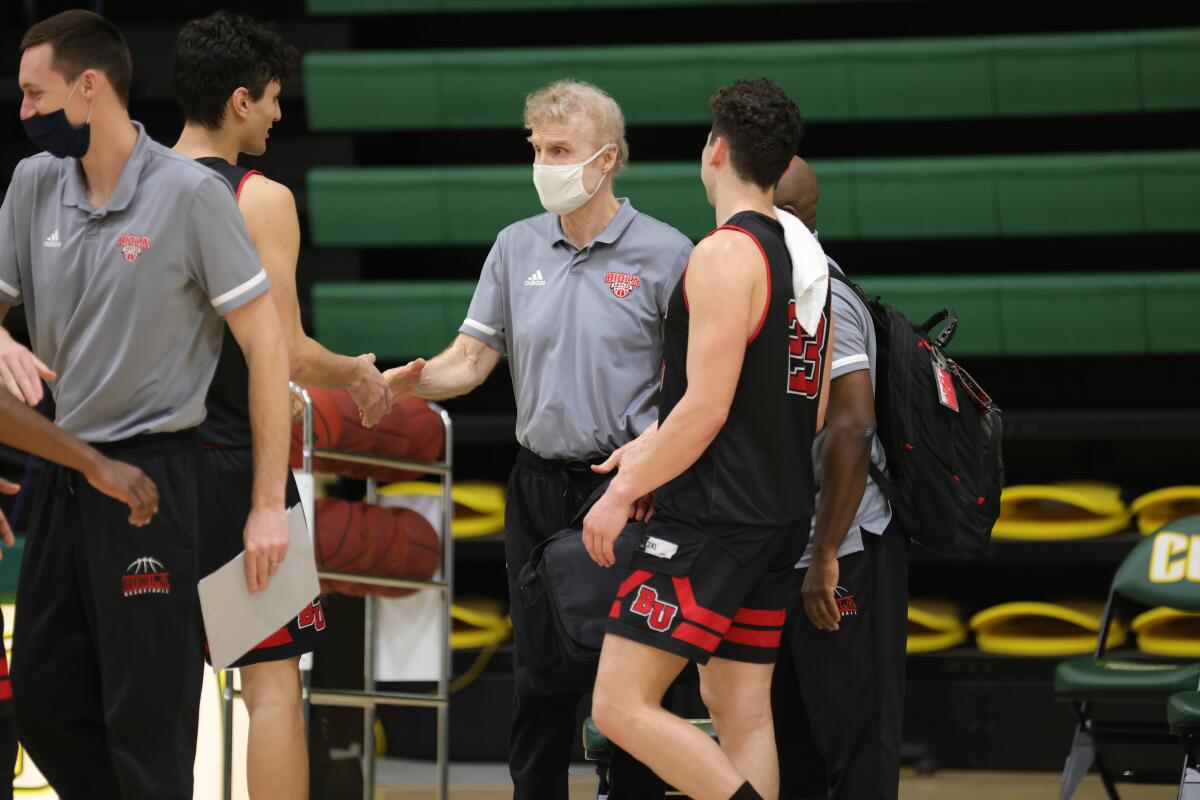 Biola men's basketball coach Dave Holmquist is congratulated by players after his 1,000th career victory on Feb. 27.