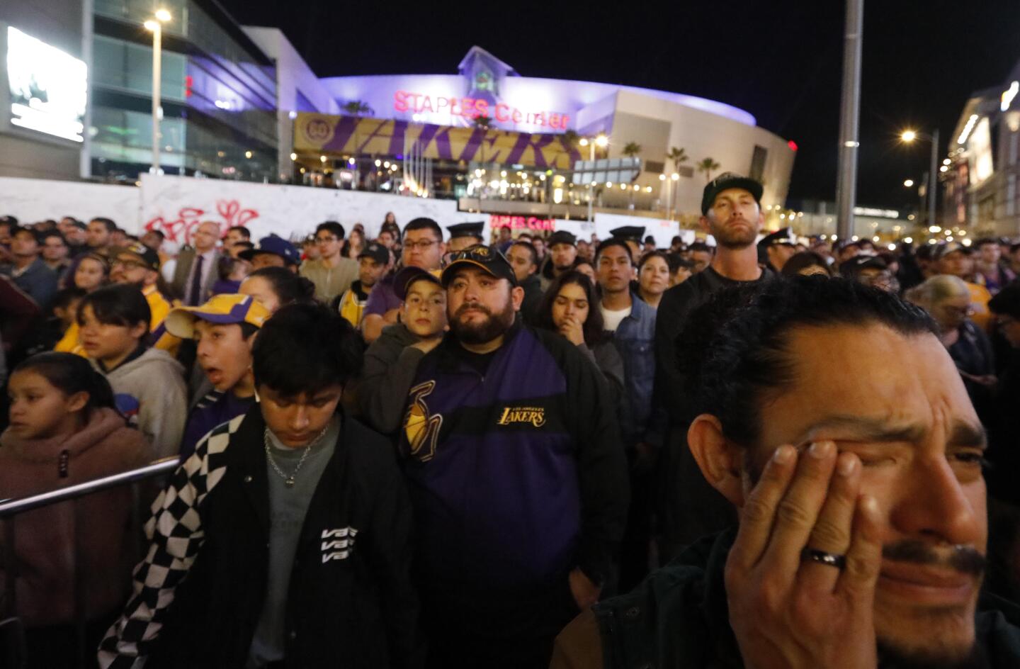 Joseph Hernandez, right, wipes a tear while watching a pregame tribute to Kobe Bryant with hundreds of fans standing outside Staples Center on Jan. 31, 2020.