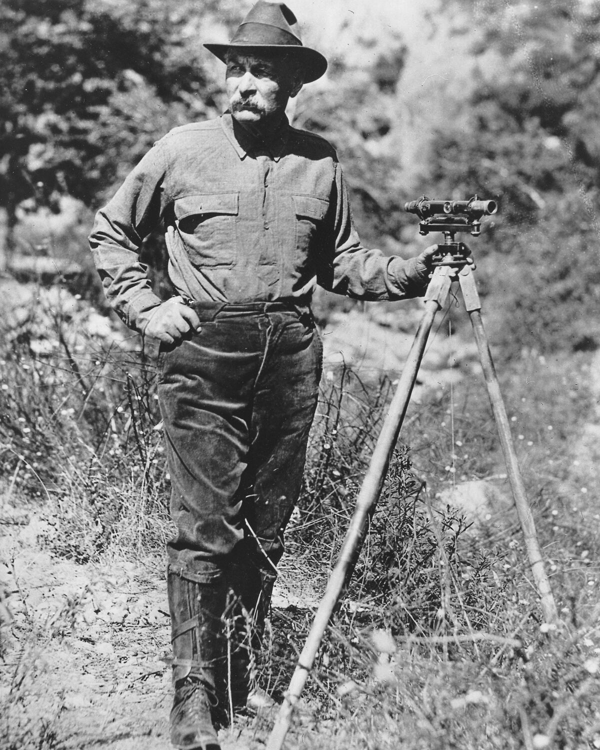 A black and white photo of a surveyor in a meadow