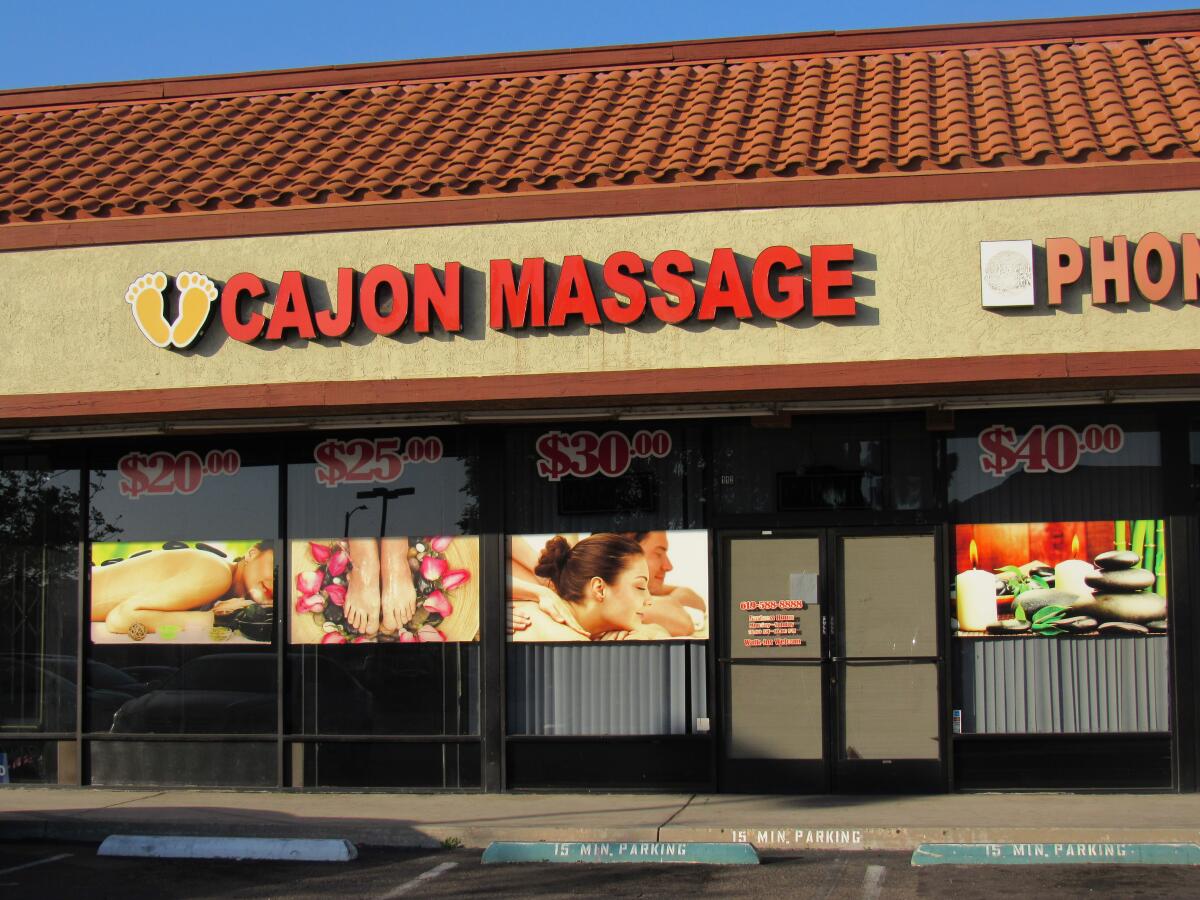Signs in the window at a storefront called Cajon Massage in a strip mall