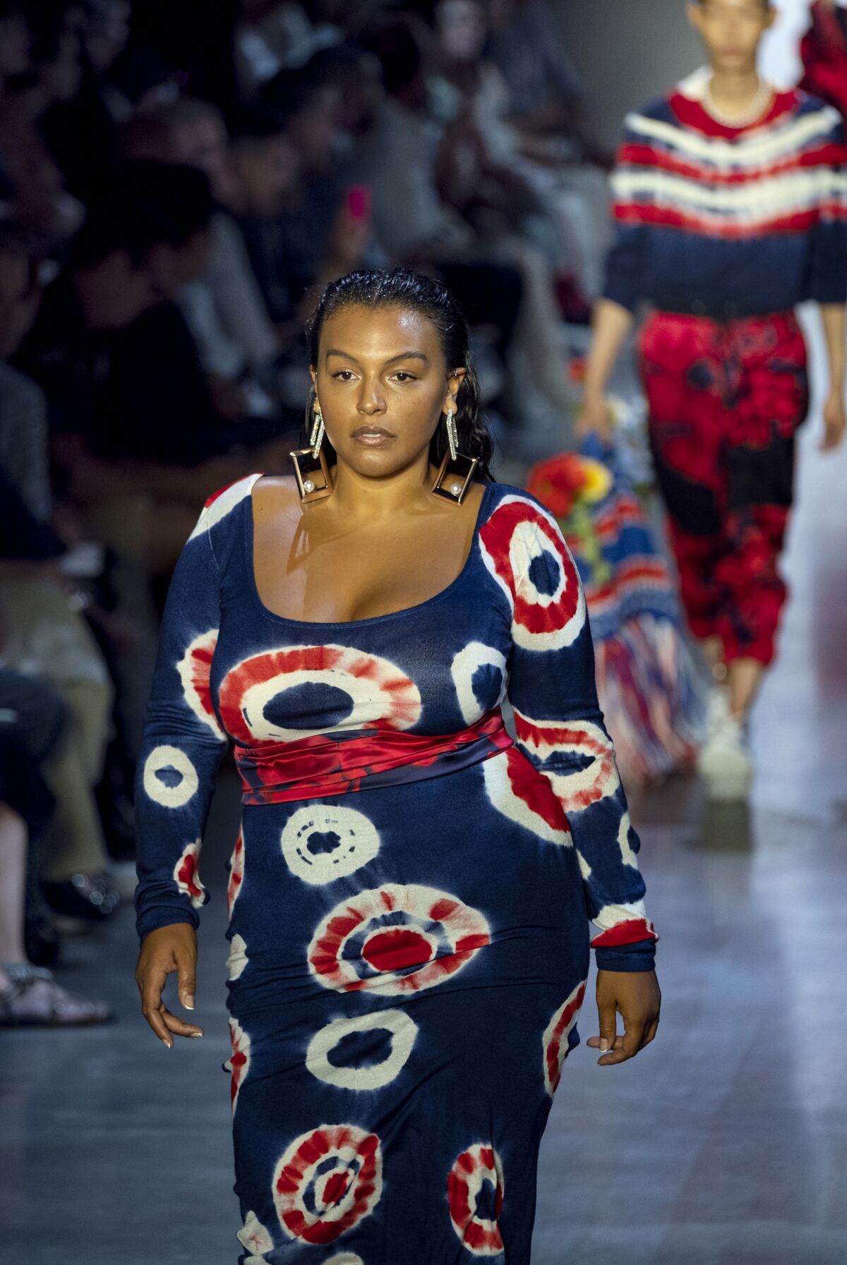 A model wears a navy blue dress with red and white tie-dye circles, a nod to Prabal Gurung's childhood interactions with American hippies in Nepal.