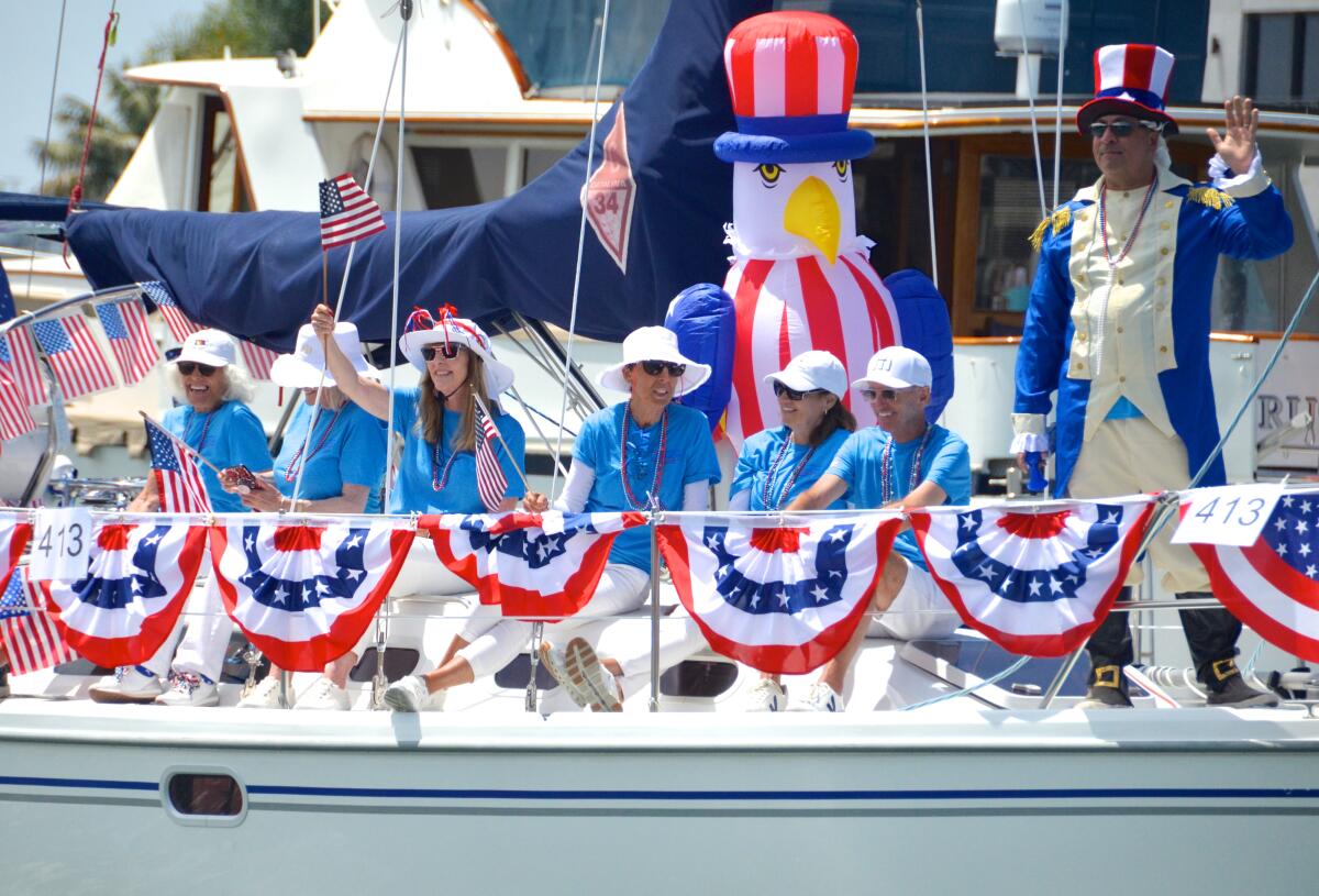 Passengers of OASIS V wave flags to people on Balboa Island during the Old Glory Fourth of July boat parade.