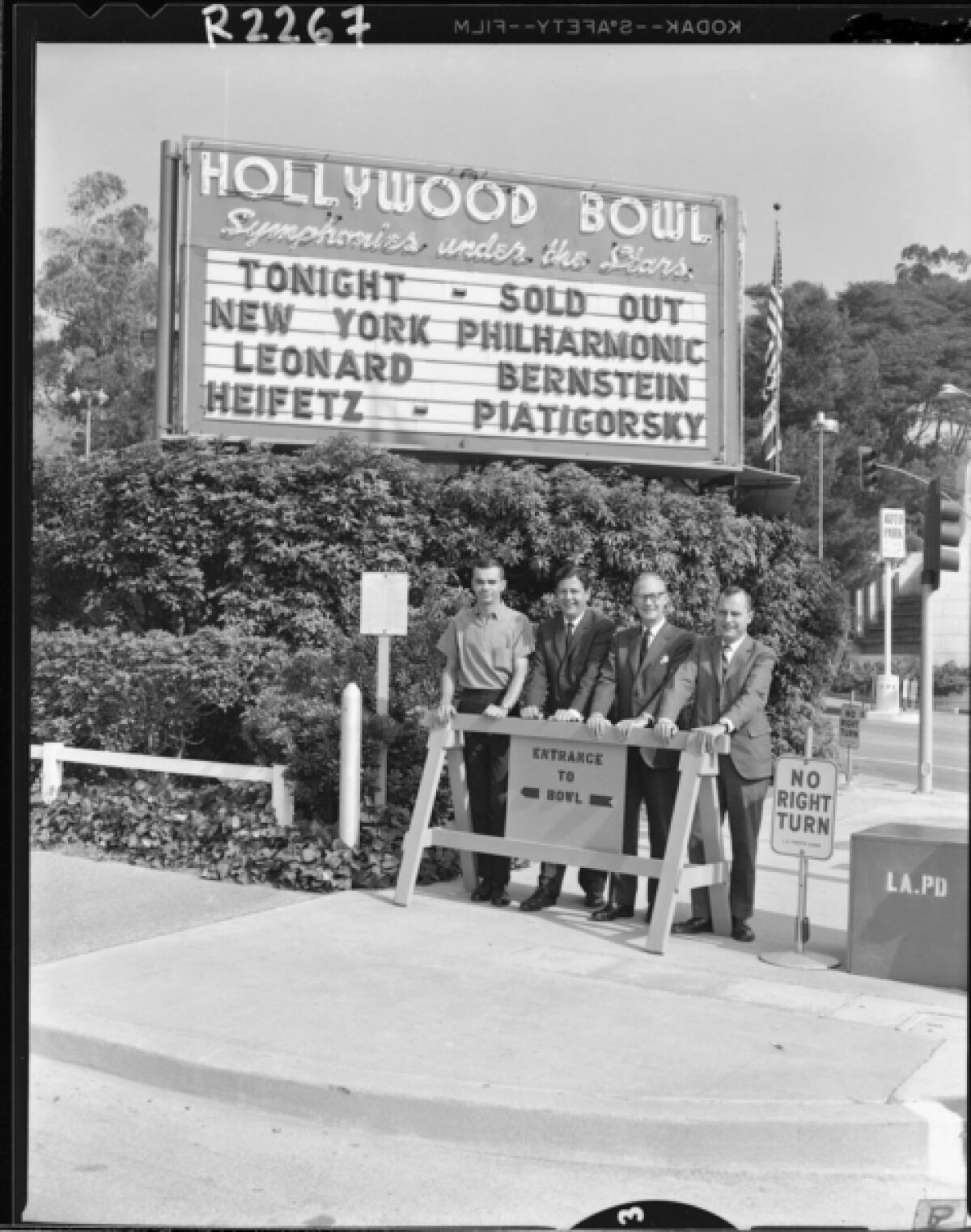Four men standing under Hollywood Bowl sign.