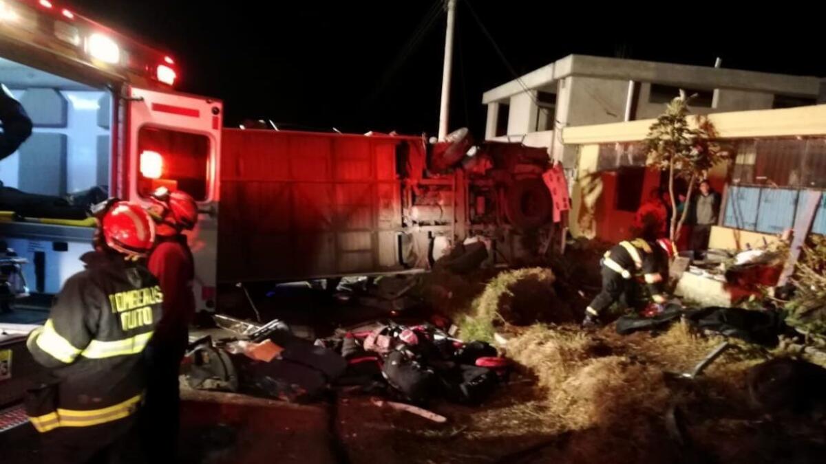 Firefighters and rescuers work at the scene where a bus crashed into another vehicle near Ecuador's capital, Quito.