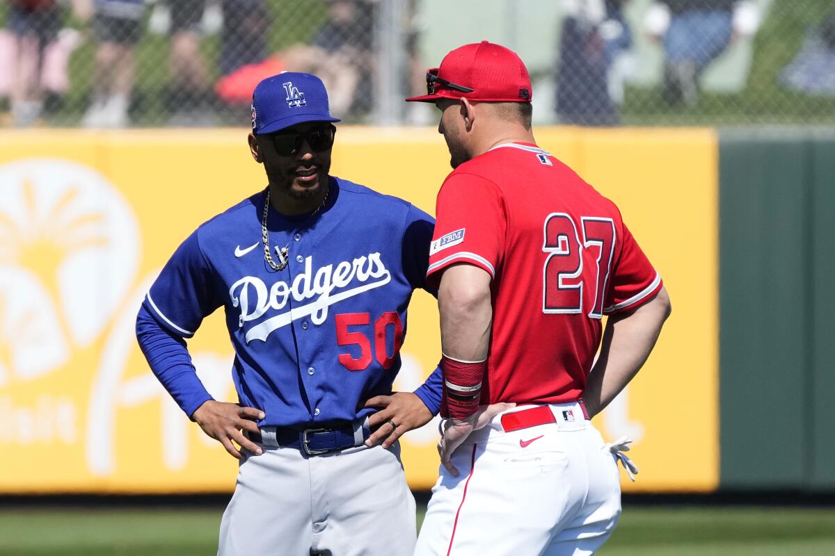 Dodgers right fielder Mookie Betts, left, talks with Angels center fielder Mike Trout before a spring game on March 3.