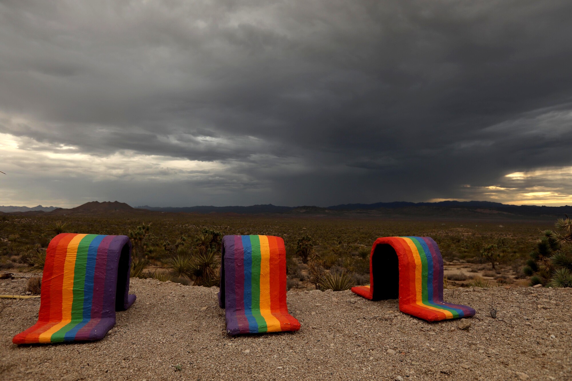 Rainbow-painted arches sit in a desert landscape.