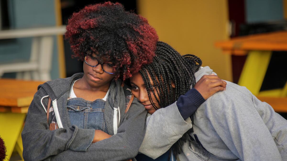 Students Zoe Miles, 14, left, and Pearl Green, 15, appear somber as they mark the last day at City High School.