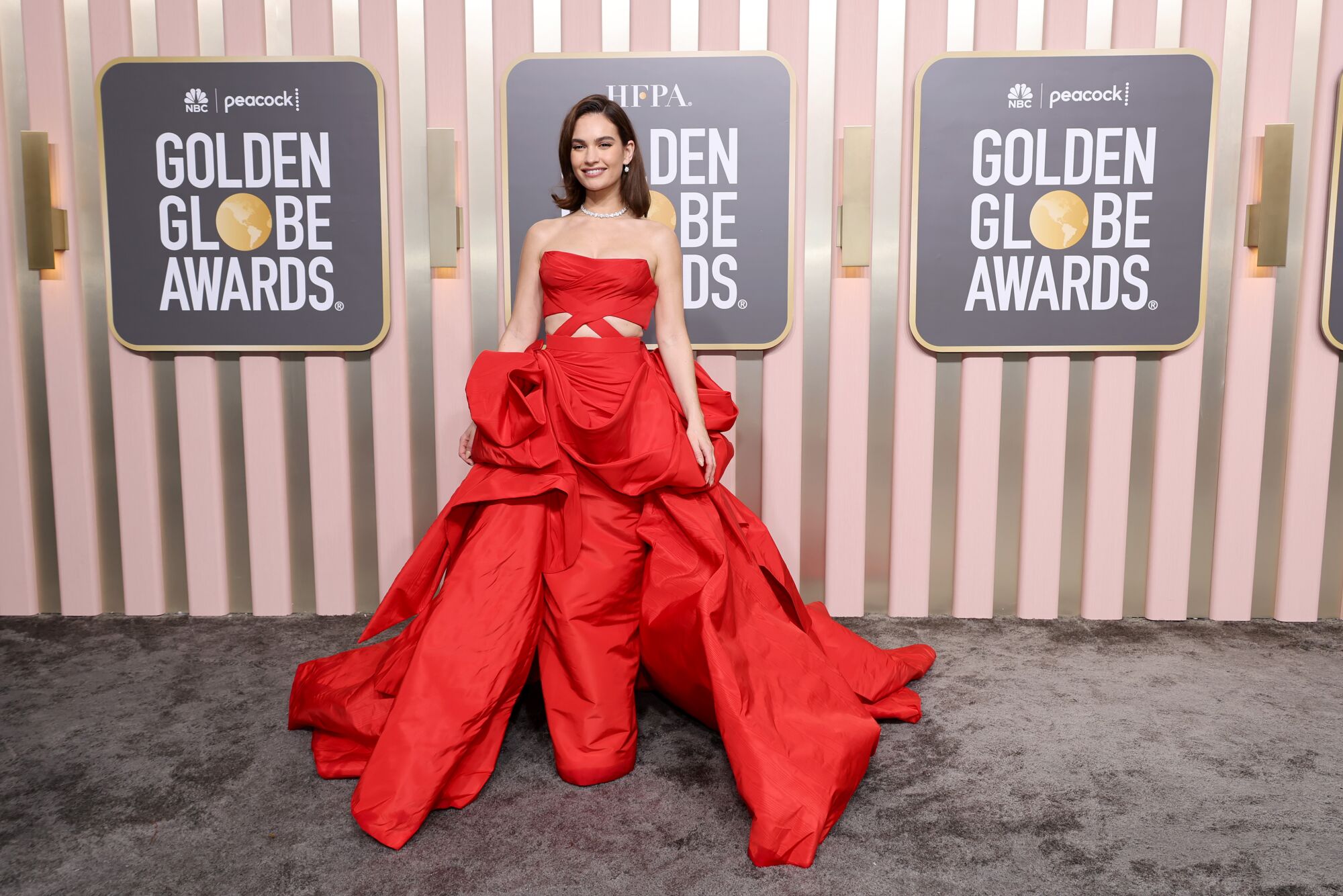 Lily James looks red hot in a custom-made Versace column gown.