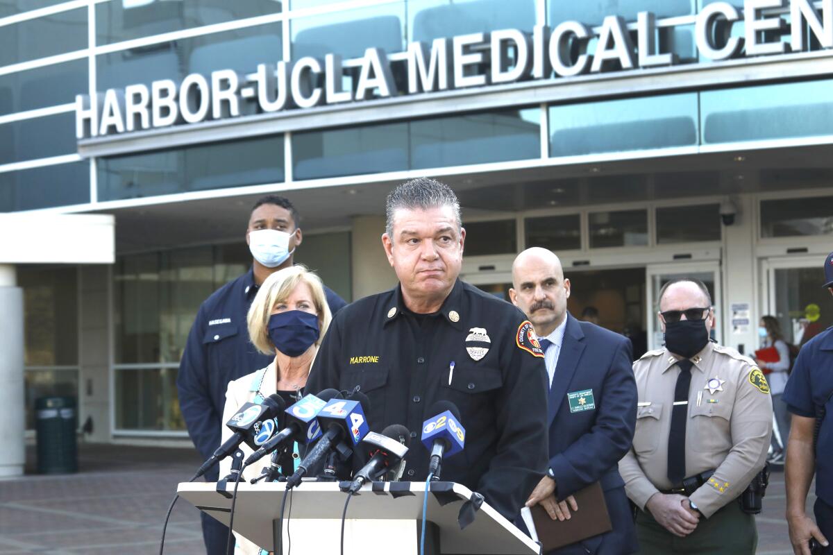 A man in a uniform stands at a lectern outside Harbor-UCLA Medical Center. 