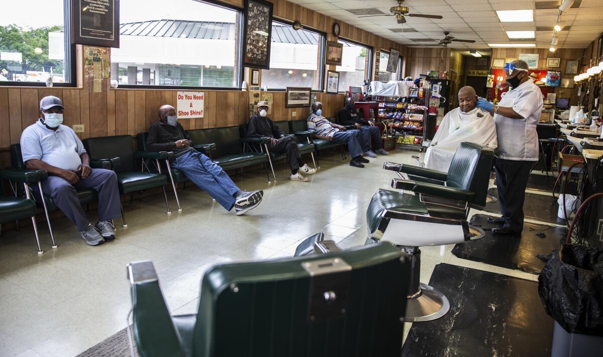 Clientes esperan su turno en la peluquería Butler's Personal Touch en Greensboro, Carolina del Norte, el viernes 22 de mayo de 2020. Muchos negocios han comenzado a reabrir después de permanecer cerrados a causa del coronavirus en el estado. (Khadejeh Nikouyeh/News & Record vía AP)