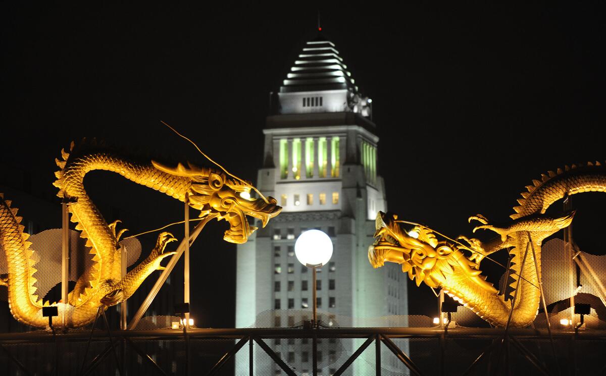 Los Angeles City Hall stands in between statues of dragons in Chinatown.