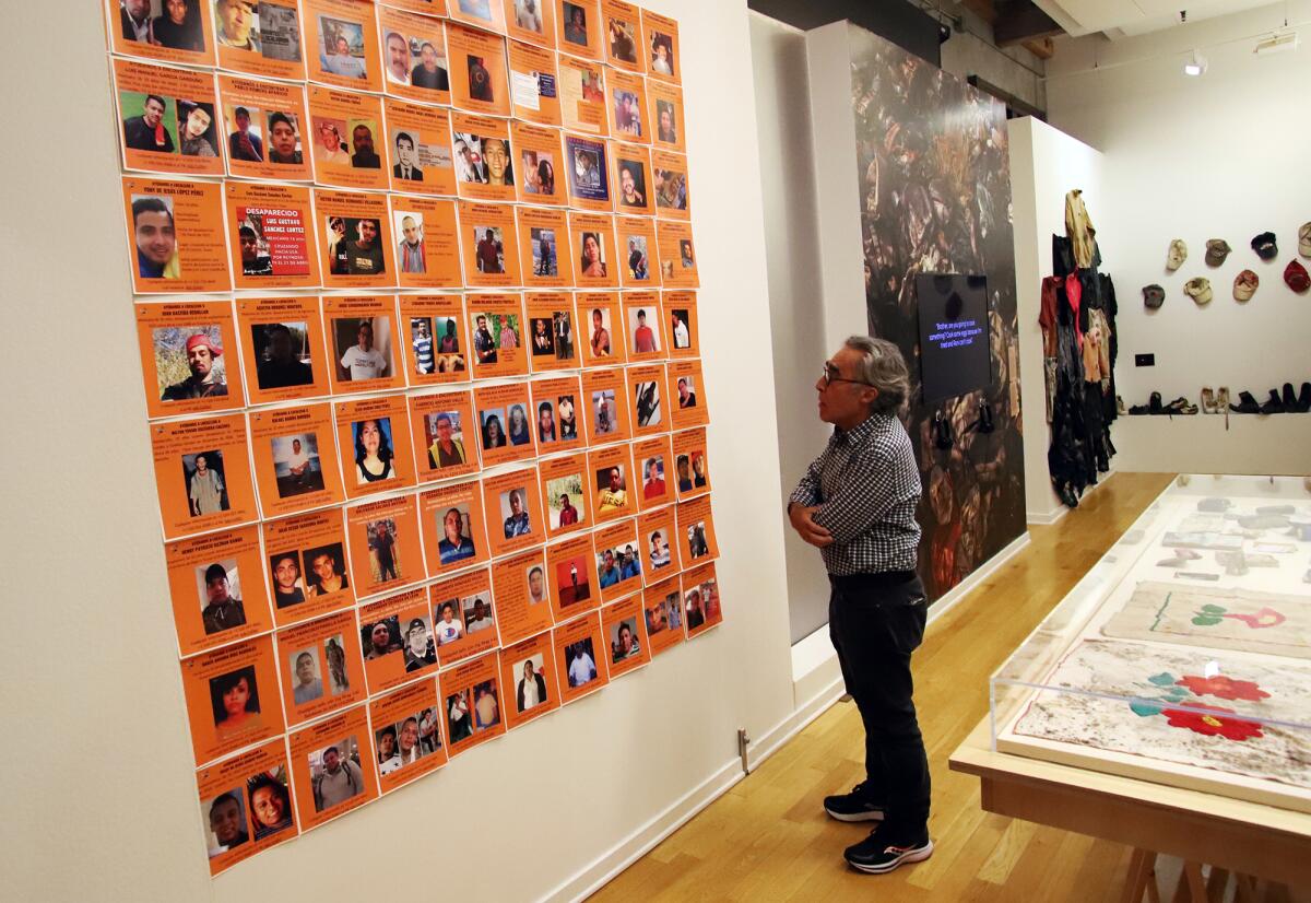 A man looks at a wall of posters.