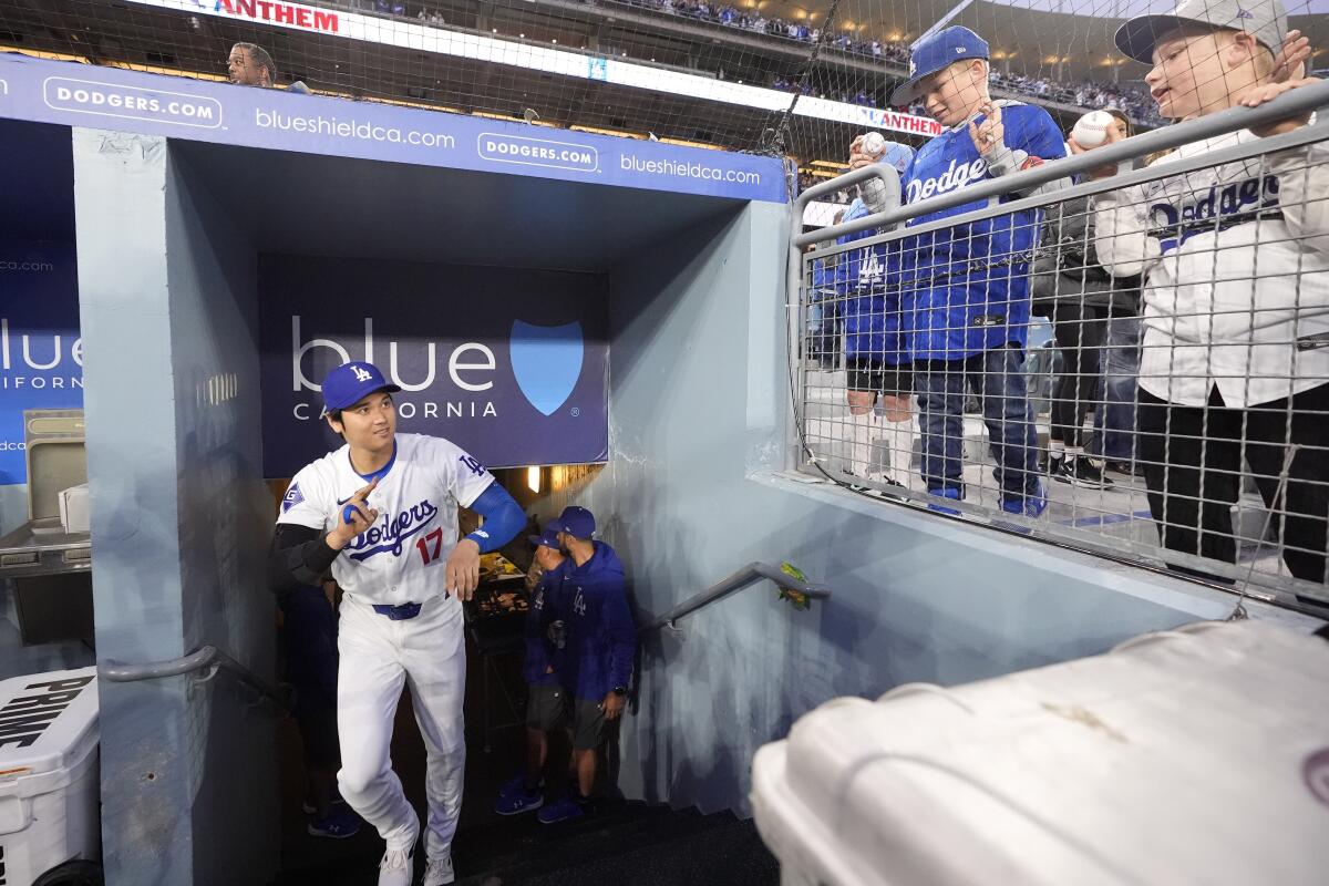Dodgers star Shohei Ohtani gestures to children as he walks into the dugout before Friday's game against the Padres.