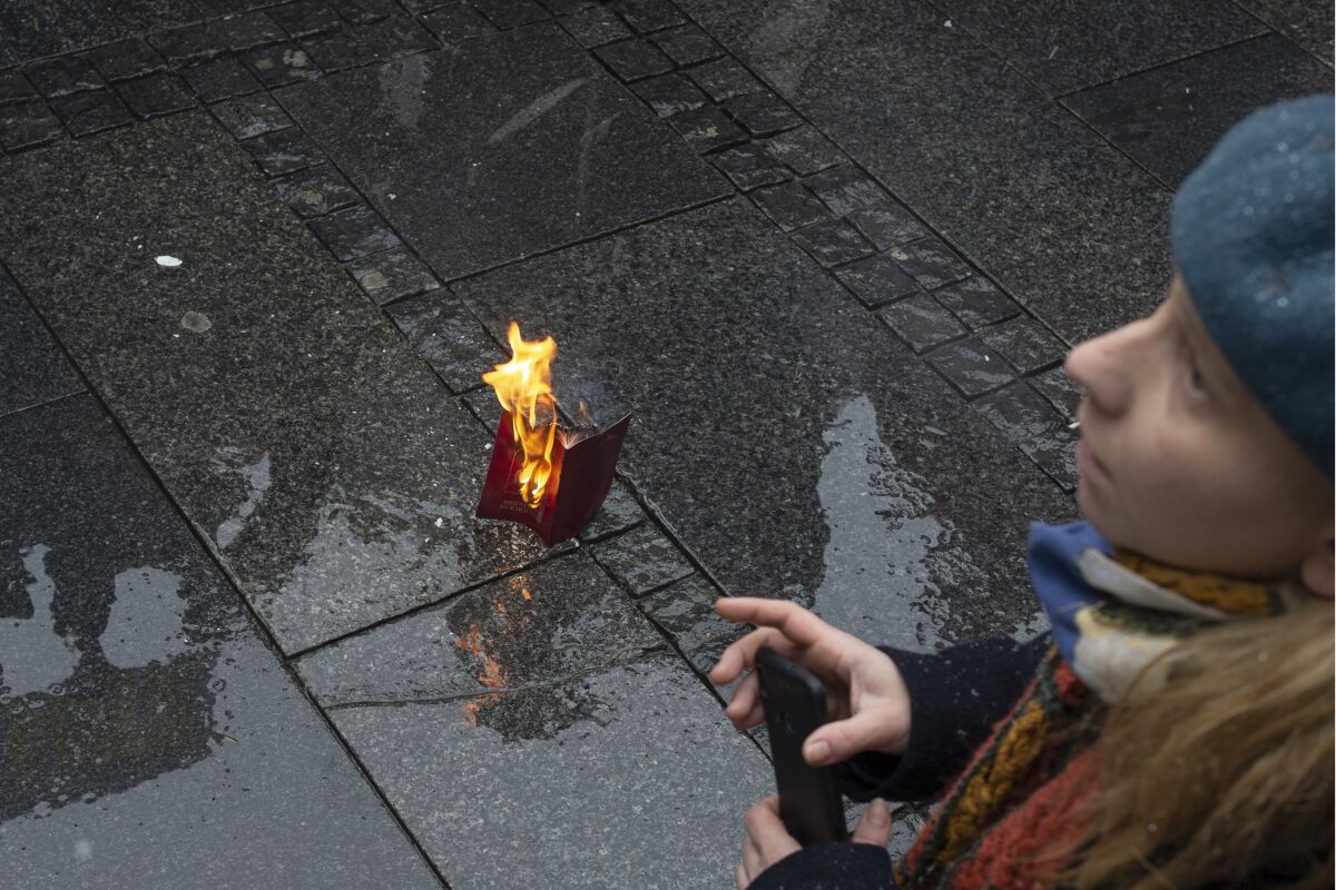 A Russian passport burns on the street during a protest against the Russian military invasion of Ukraine, in Belgrade, Serbia, Sunday, March 6, 2022. A group of Russian citizens living in Serbia were among dozens of people on Sunday who braved freezing weather and a late winter blizzard to gather in central Belgrade in support of Ukraine and against the war that in the past 11 days has claimed scores of lives and driven 1.5 million people from their homes. (AP Photo/Marko Drobnjakovic)