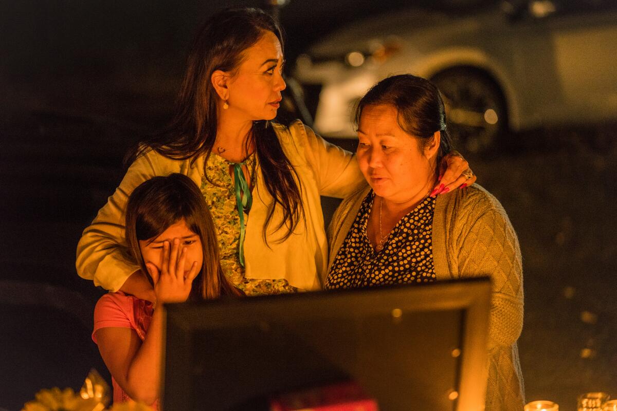 Hmong community advocate Paula Yang consoles Dayvina Xiong, 6, and Bao Xiong as they and other family members held a candlelight vigil for four men who were shot and killed Nov. 17 in Fresno.