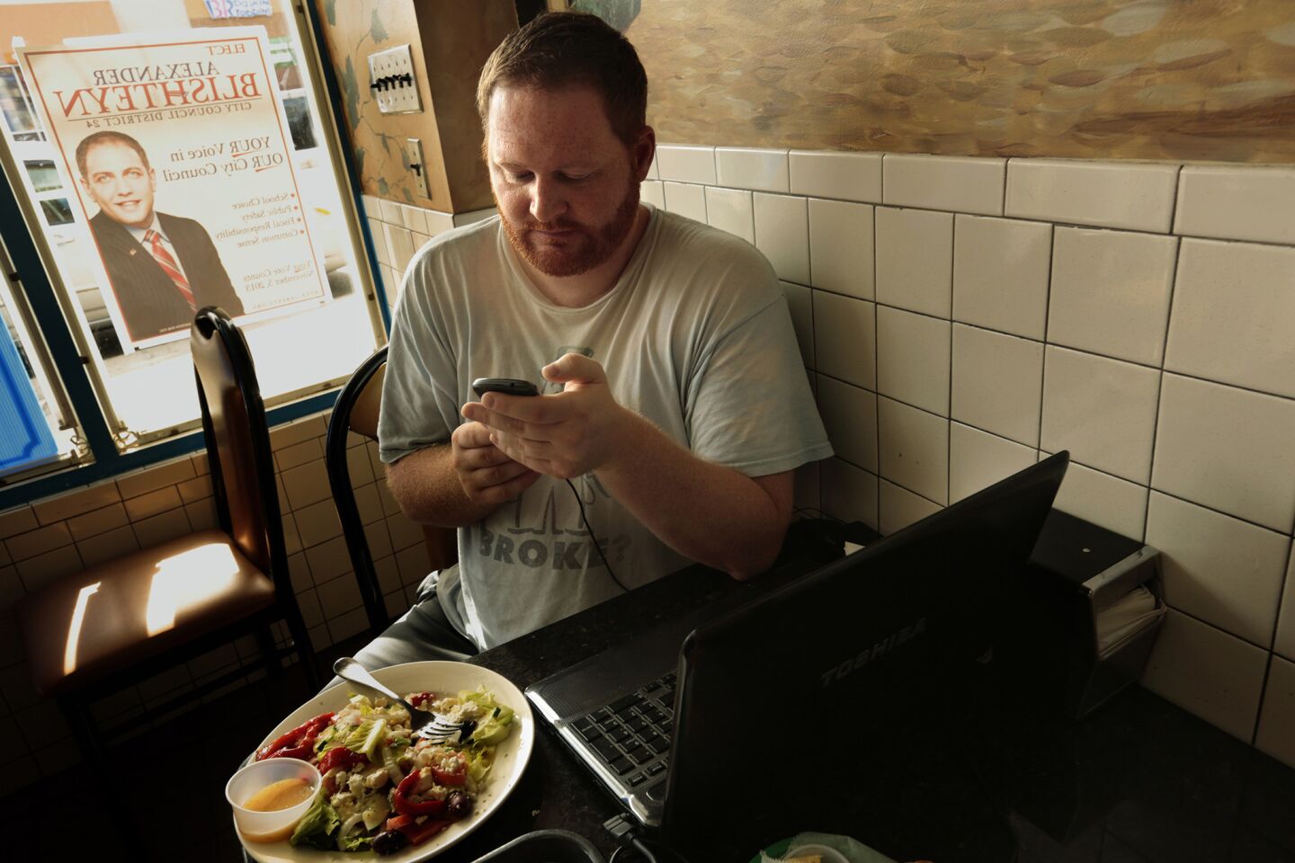 Without electricity in his RV, Hall charges his computer and cellphone at local restaurants.