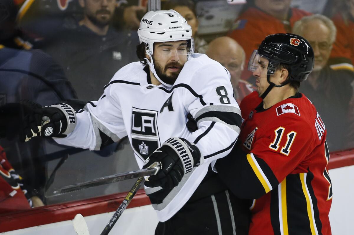 Kings' Drew Doughty, left, is checked by Calgary Flames' Mikael Backlund during the first period on Tuesday in Calgary, Canada.