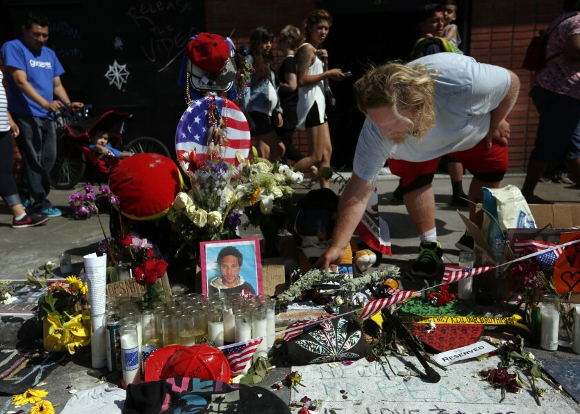 Bruce Chartier, 30, places sage on a memorial for his friend Brendon Glenn in Venice.
