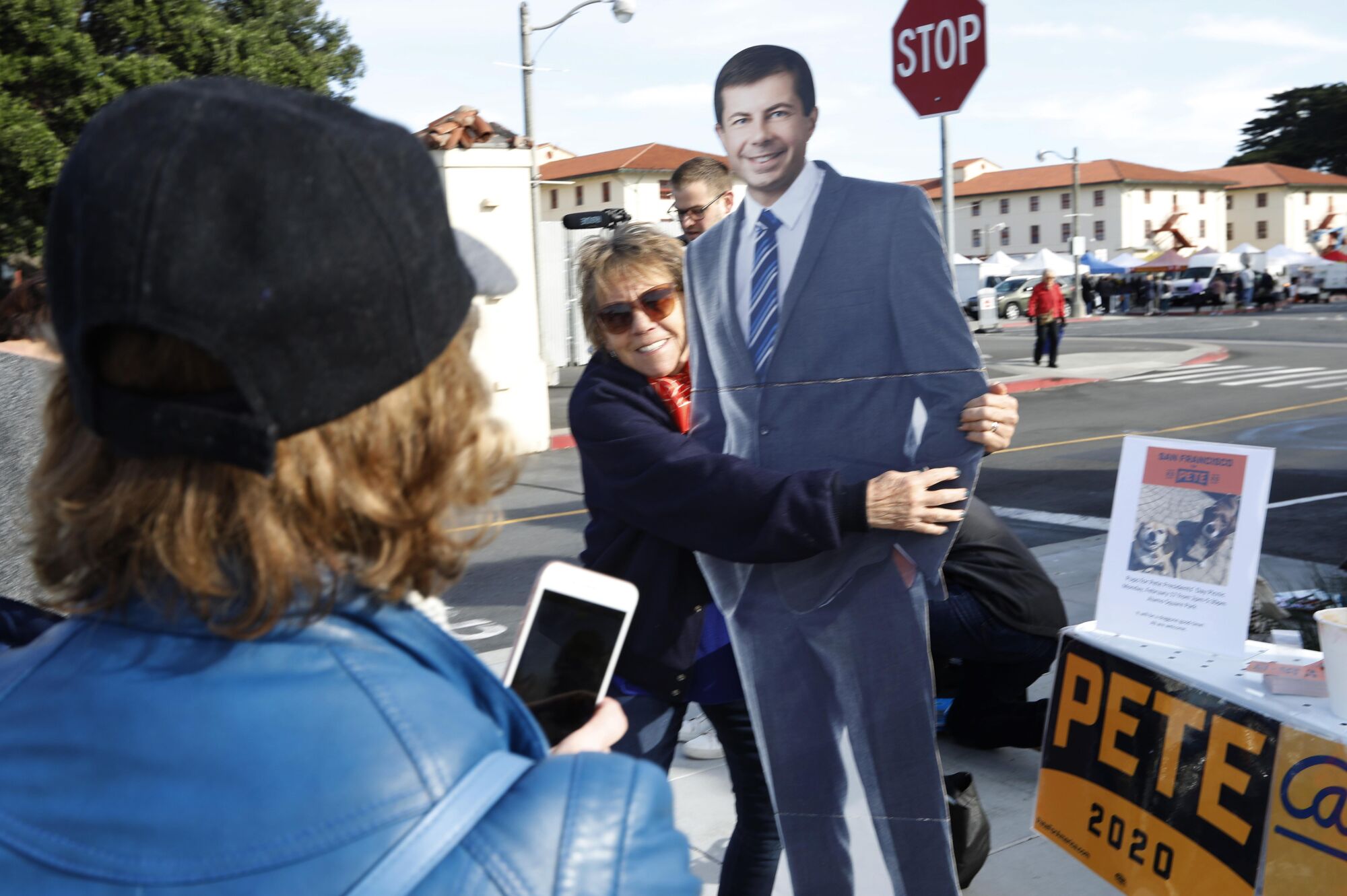 People pose with a cardboard cutout of Pete Buttigieg near the Fort Mason farmers market