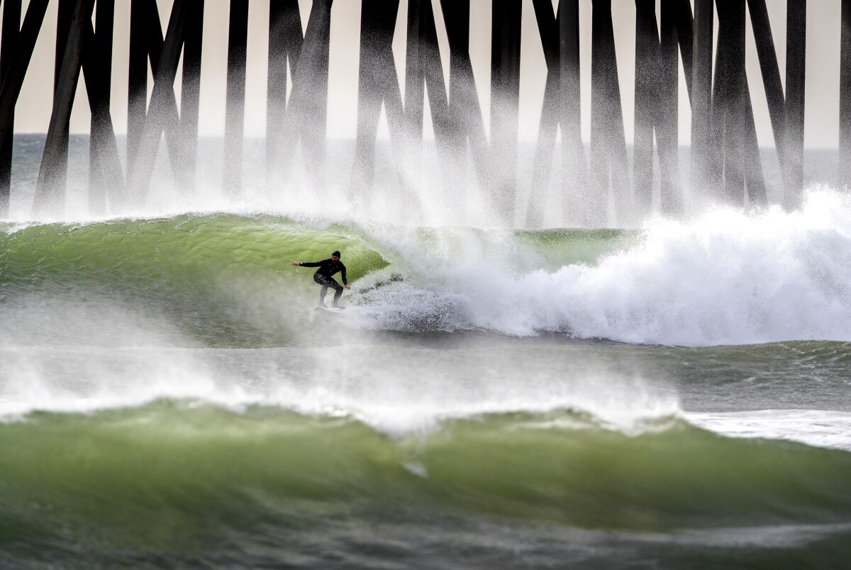 Huntington Beach, CA - January 19: Surfers ride waves sculpted by gusty Santa Ana winds at the Huntington Beach pier on Tuesday, Jan. 19, 2021. (Allen J. Schaben / Los Angeles Times)