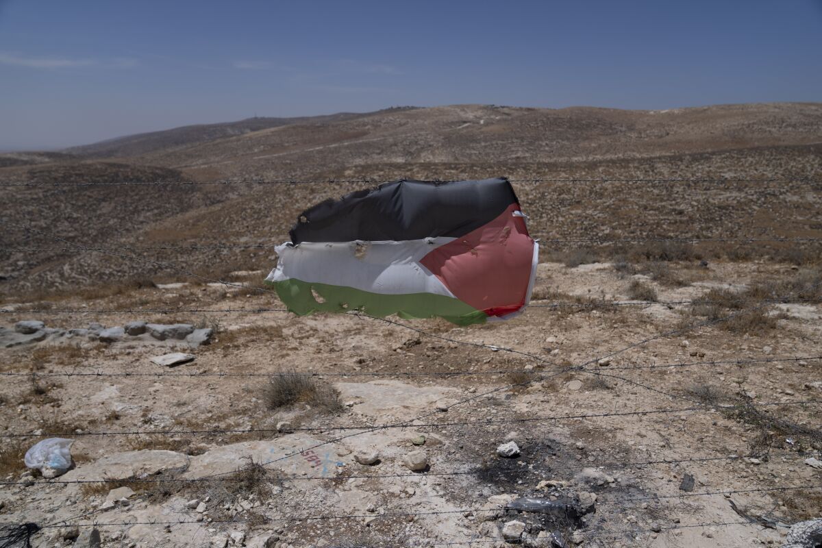 A Palestinian flag is posted at a barbed wired at the Palestinian hamlet of Khallat al-Dhaba, in the cluster of Bedouin communities in Masafer Yatta, West Bank, Monday, Aug. 1, 2022. Palestinians living in Masafer Yatta, in the occupied West Bank, fear they could be expelled at any time after Israel's Supreme Court ruled in favor of the military earlier this year in a two-decade legal battle. (AP Photo/Nasser Nasser)