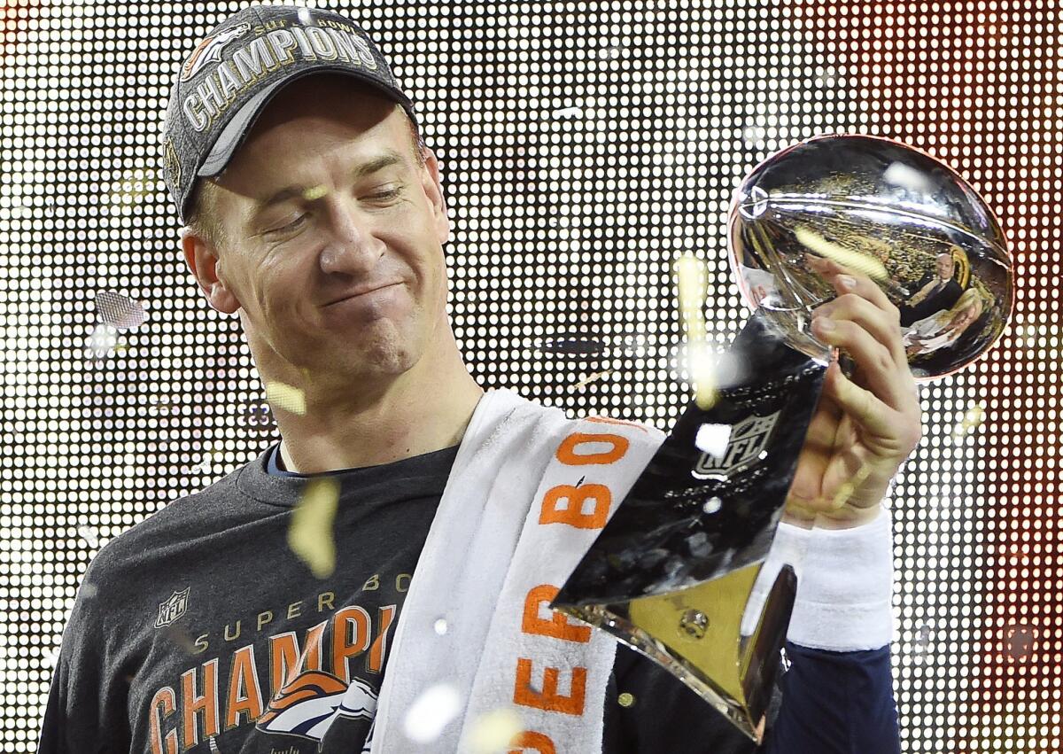 Denver Broncos quarterback Peyton Manning admires the Lombardi Trophy after winning Super Bowl 50.