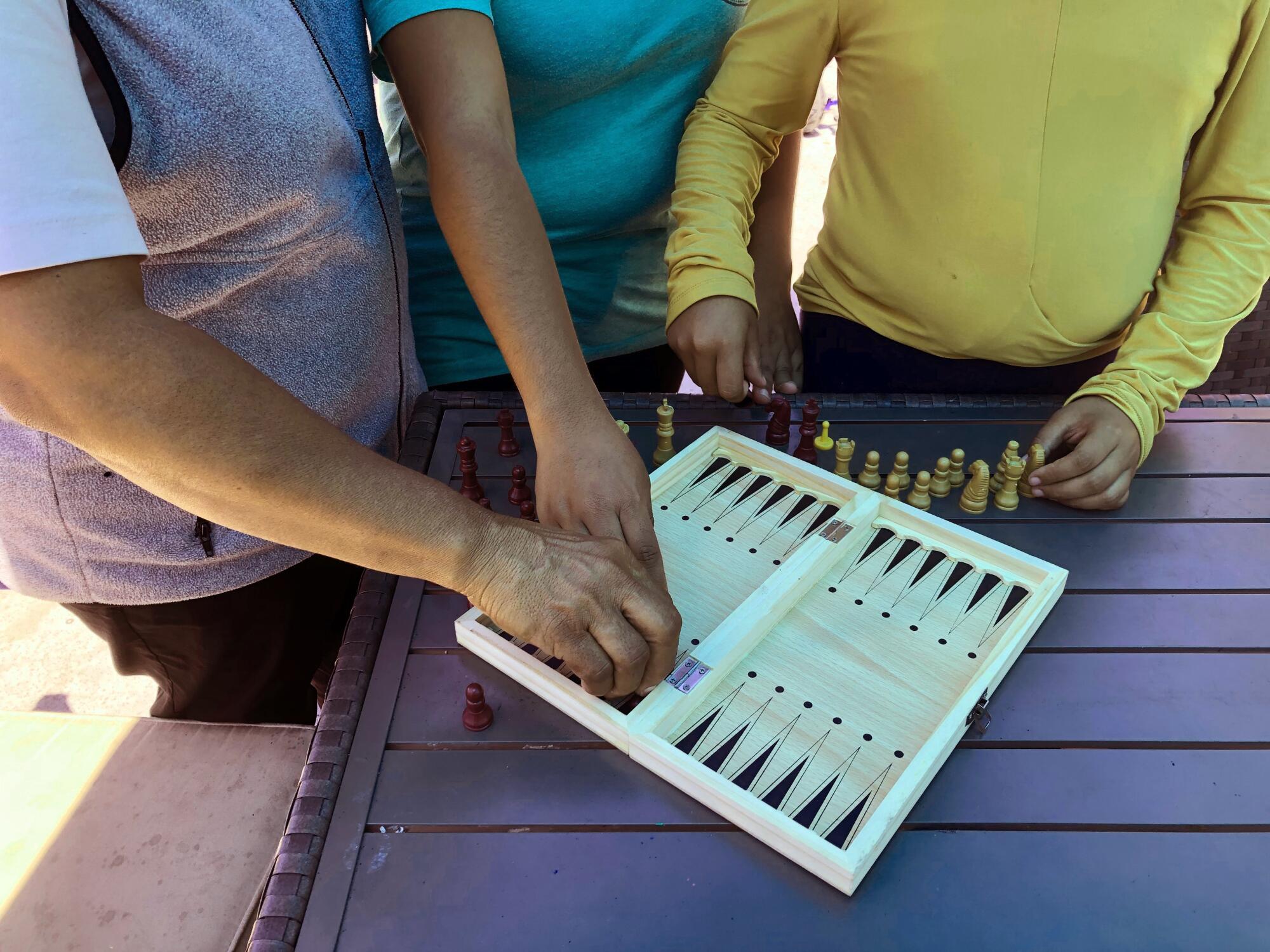 A woman arranges game board with her daughters
