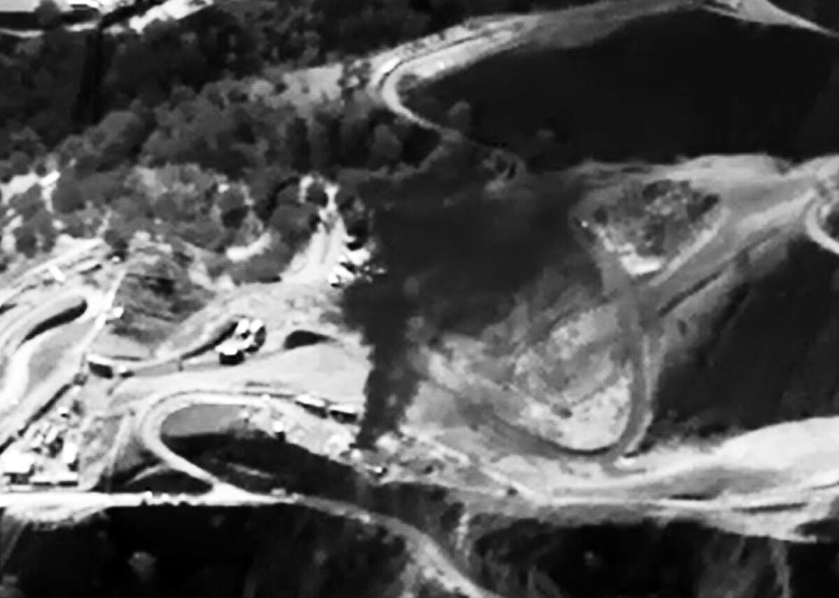 An aerial view shows gas escaping and rising in a cloud.