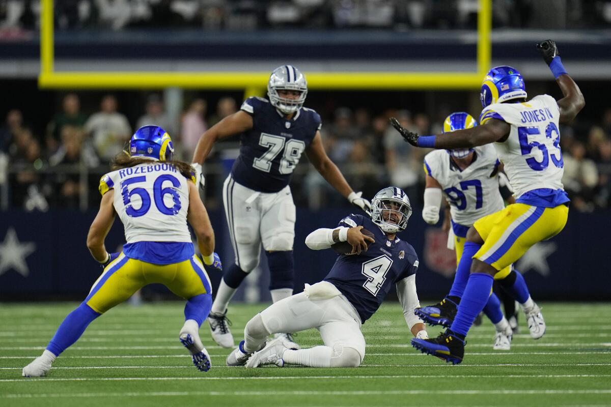 Cowboys oyun kurucusu Dak Prescott (4), Rams defans oyuncuları Christian Rozeboom (56) ve Ernest Jones'un (53) önünde kayıyor.