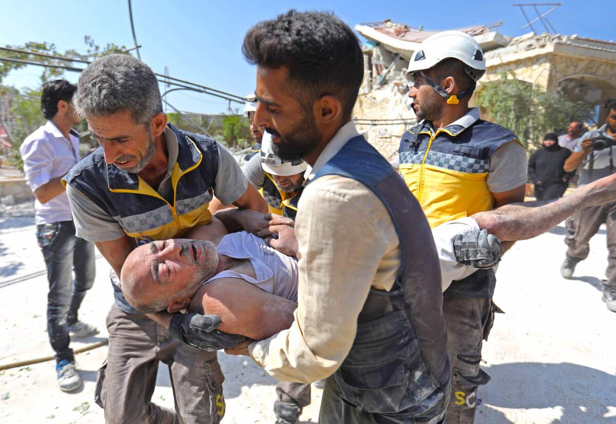 Members of the Syrian Civil Defense carry an injured man after removing him from a building that collapsed during reported airstrikes in the village of Beinin on Tuesday.