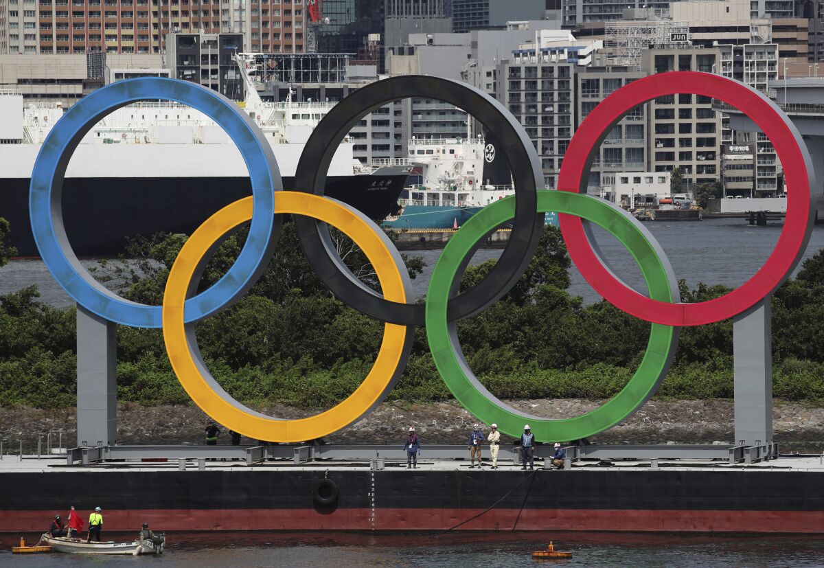 Foto del 11 de agosto del 2021, trabajadores se preparan para remover ls gigantescos anillos olímpicos