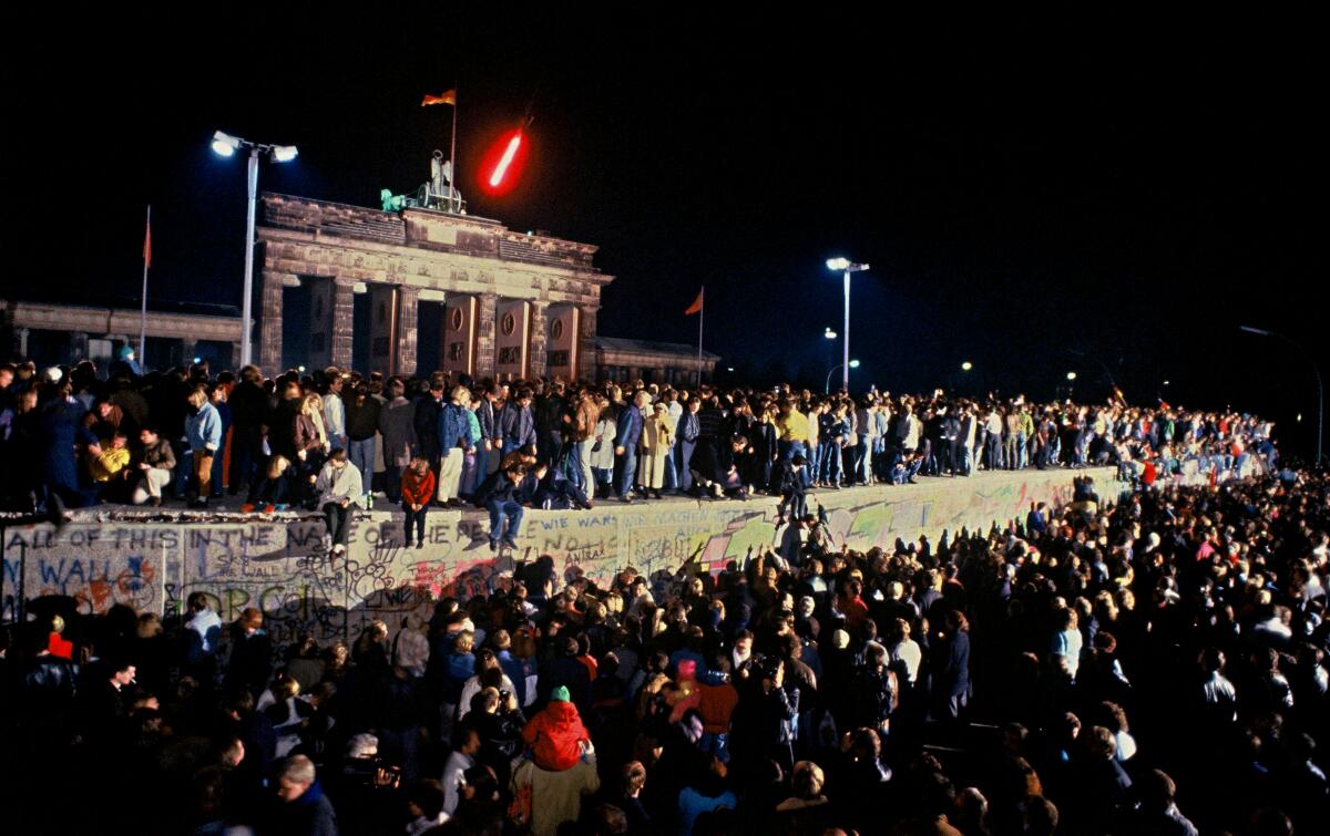 El Muro de Berlín frente a la Puerta de Branderburgo en la noche del 9 de noviembre de 1989. Miles de celebrantes lo treparon cuando se difundió rápidamente la noticia de que el gobierno de Alemania Oriental comenzaría a otorgar visas de salida a cualquiera que quisiera ir a Occidente.