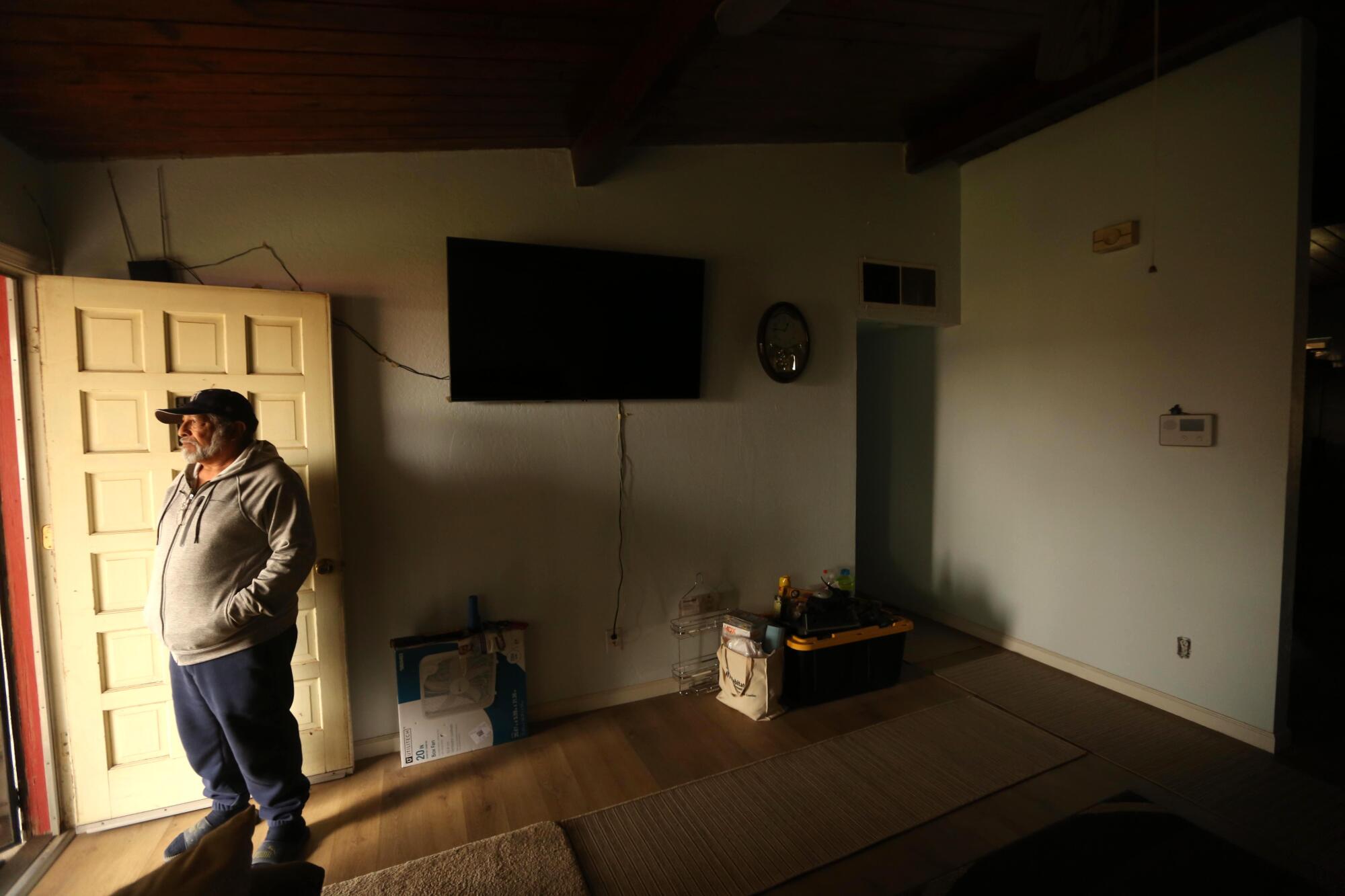 A man stands inside a home being refurbished.  