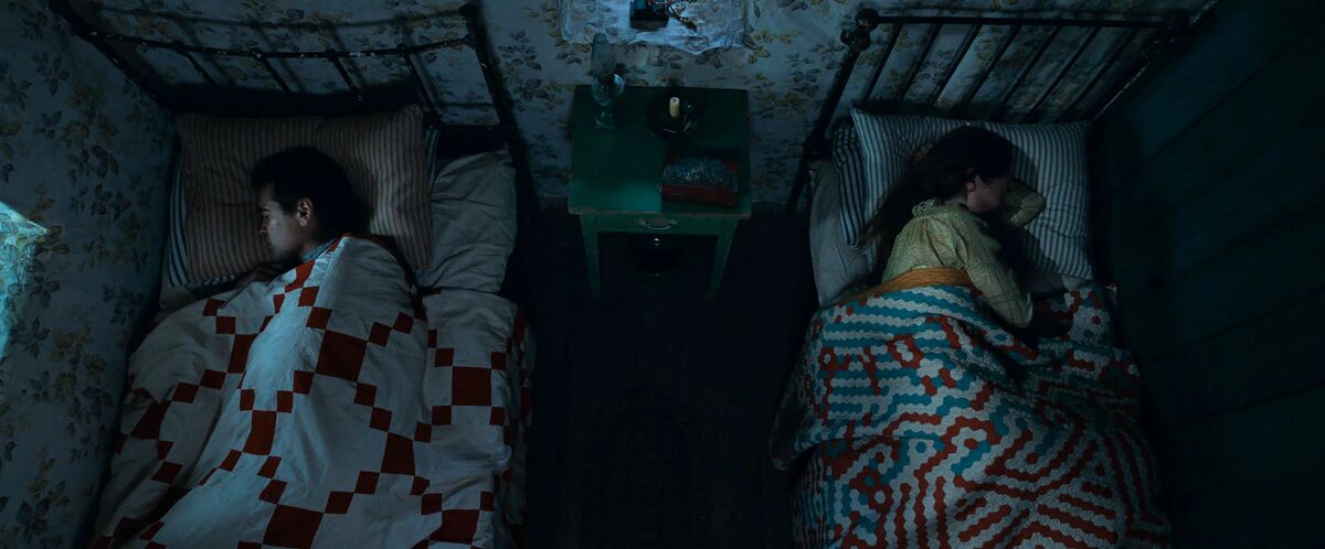 overhead shot of people sleeping facing away from each other in two twin beds
