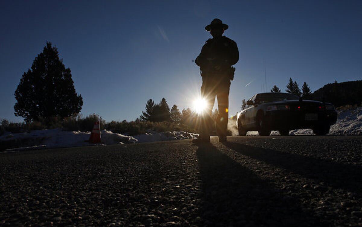A California Highway Patrol officer mans a roadblock on California 38 on Feb. 13, near where Christopher Dorner fired on two San Bernardino County sheriff's deputies, killing one. The second deputy returned to work Monday.