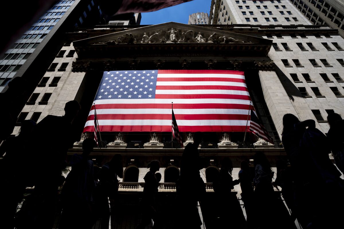 A view of the New York Stock Exchange with a large American flag on the building.
