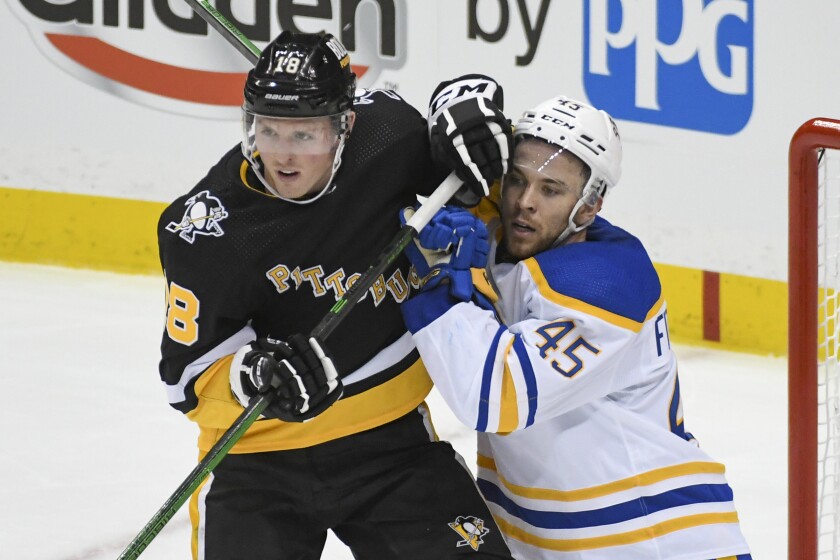 Pittsburgh Penguins winger Sam Lafferty (18) and Buffalo Sabres defenseman Casey Fitzgerald (45) battle for position during the third period of an NHL hockey game on Friday, Dec. 17, 2021, in Pittsburgh. (AP Photo/Fred Vuich)