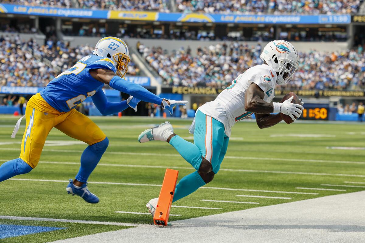 Dolphins receiver Tyreek Hill catches a pass near the goal line as Chargers cornerback J.C. Jackson pursues.