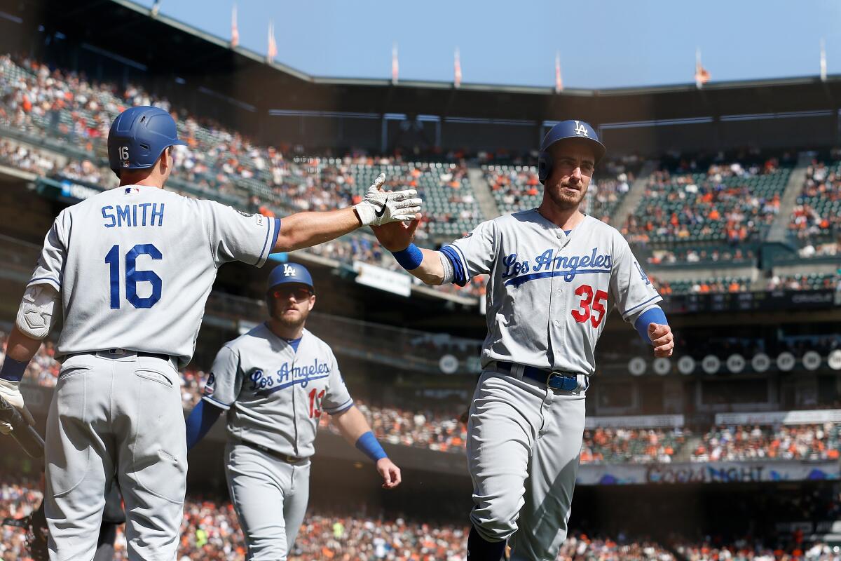 Cody Bellinger (35) and Max Muncy (13) celebrate with Will Smith (16) in a game against the Giants on Sept. 29 at Oracle Park.
