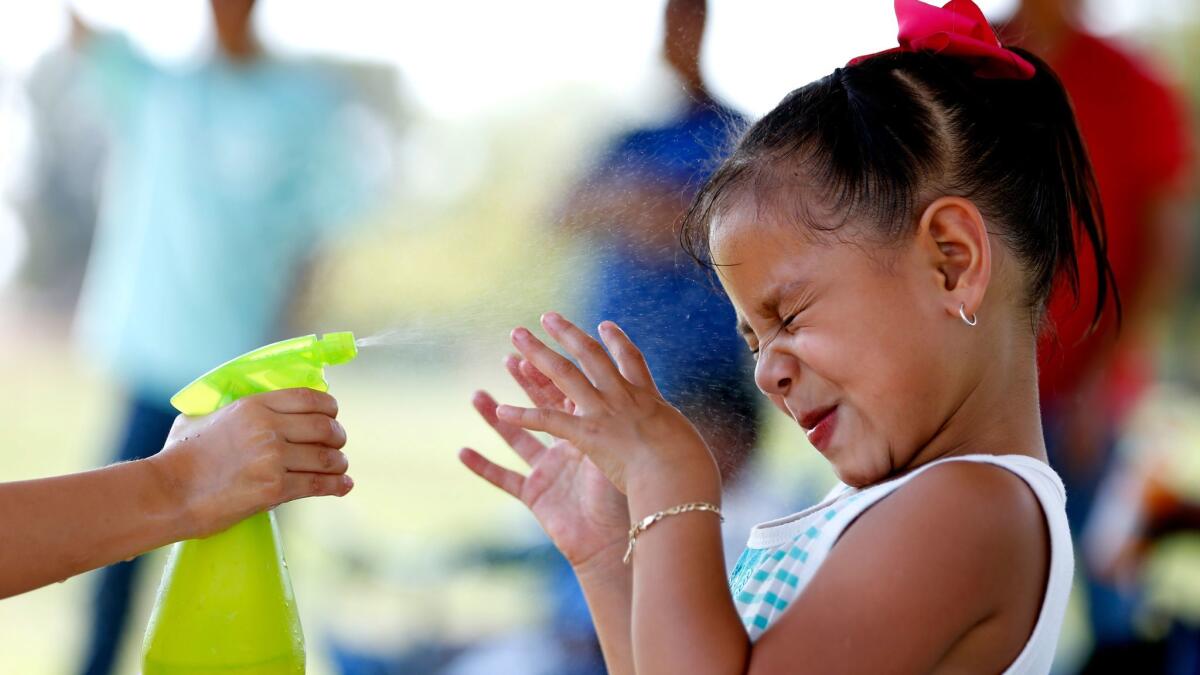 Samantha Tlaxcalteco, 4, left, of Winnetka, sprays her friend Cynthia Torres, 5, of Canoga Park, with cold water at the Balboa Sports Center in Encino.